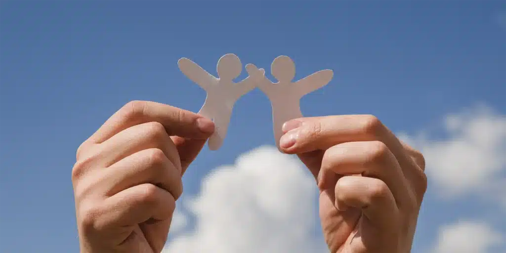 hands holding paper cutouts of people