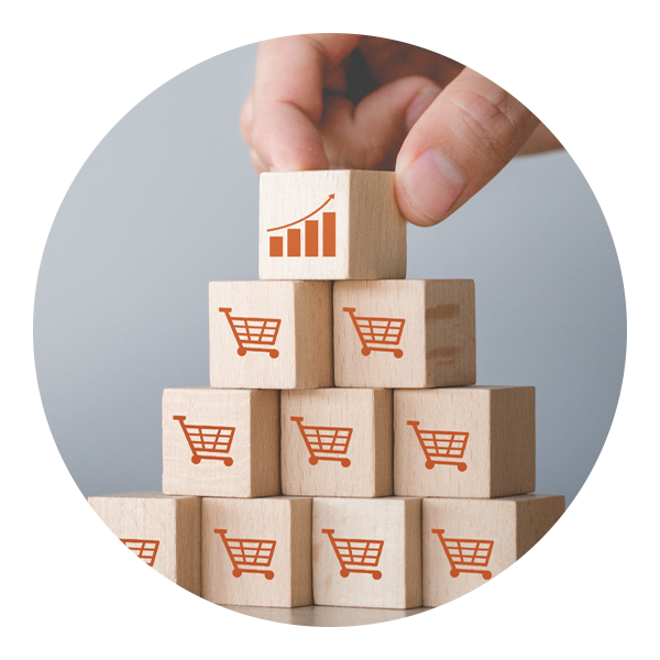 A hand stack building blocks with shopping cart images on them, with the top one having a graph charting upwards